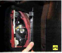 3. Сожмите фиксаторы и откройте крышку в облицовке багажника для доступа к заднему
