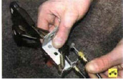 6. Выньте из прорези кронштейна блока рычагов наконечник оболочки троса привода